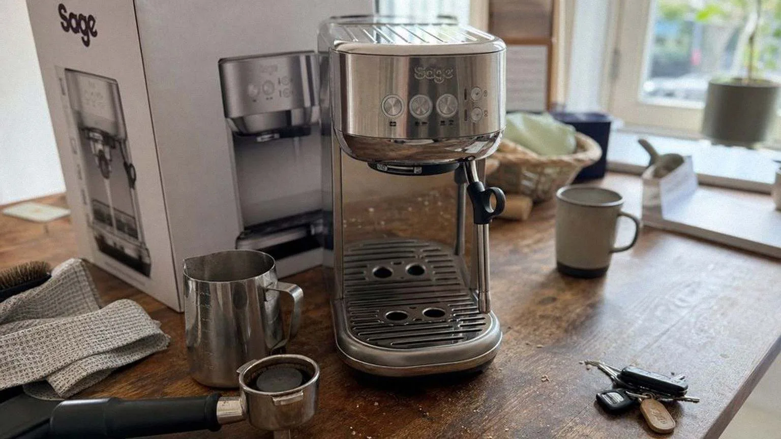 The Bambino Plus on a domestic worktop in morning light, a milk jug and a portafilter beside it.